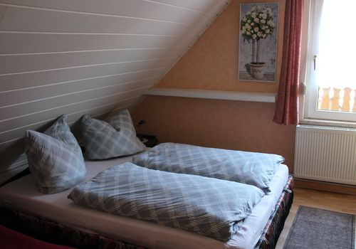 Eines der beiden Schlafzimmer im Dachgeschoss mit Doppelbett und Zusatzbett.<br>(Bild: harztourist)