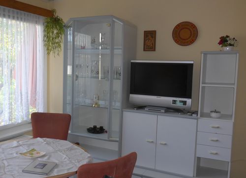 Helles Wohnzimmer mit Sitzecke und großem Flachbildschirm-TV